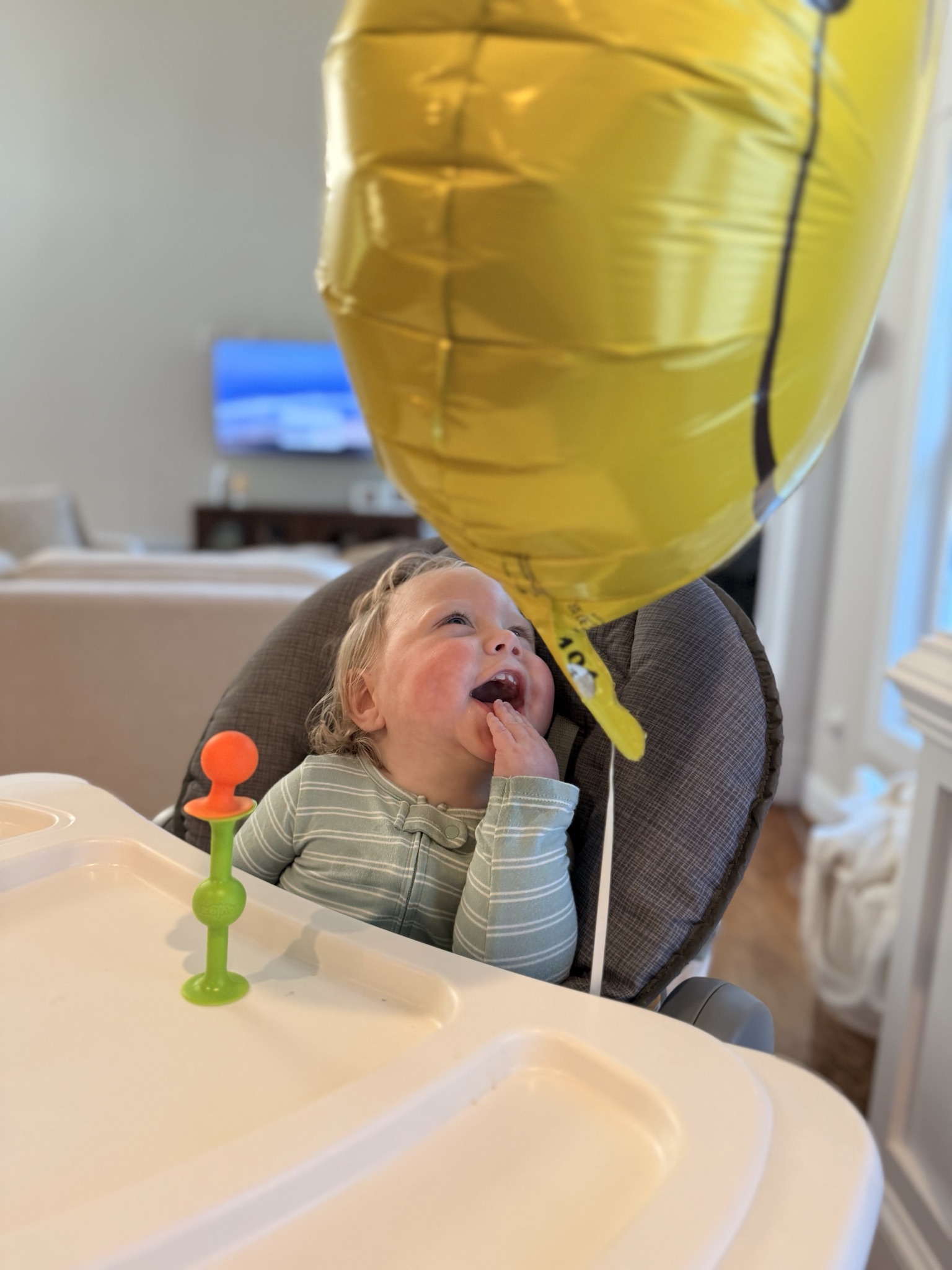 Oliver laughing while looking up at a yellow balloon